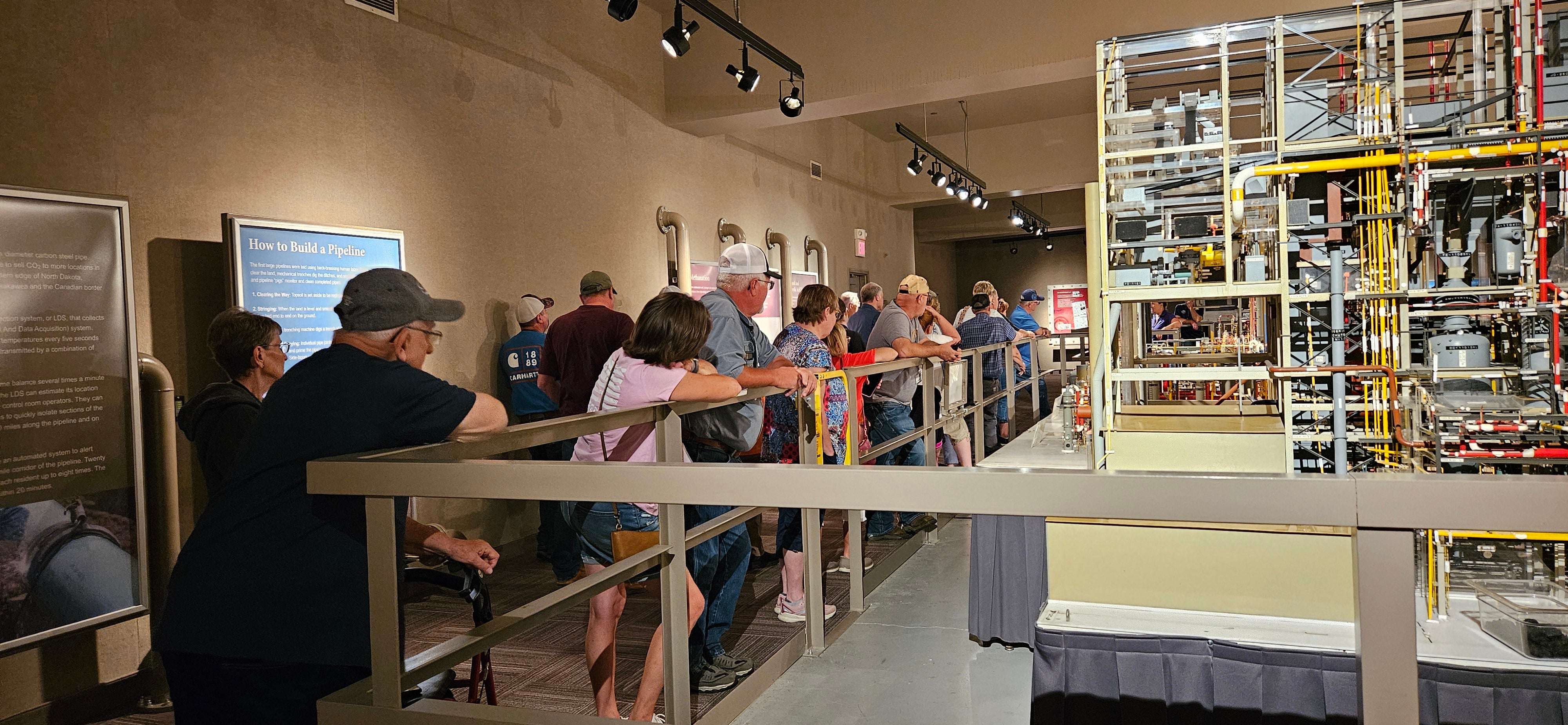 At Dakota Gasification Company, members gather around a scale model of the plant that fills a whole auditorium. 
