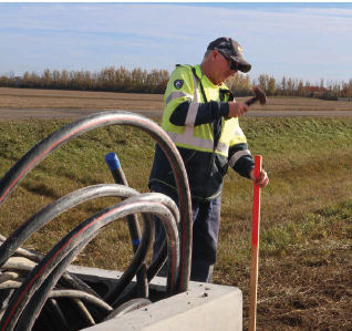 Journeyman Lineman Tyler Marken pounds in a stake to mark where underground cable will go.